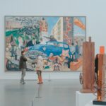 man and woman standing in front of painting in gallery