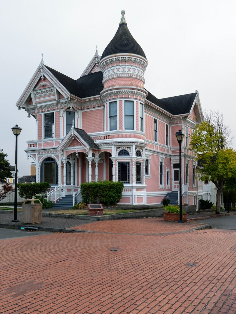 white and pink house near lampposts and road during day