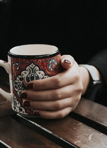 Red Interior Design Ideas Elegant Hand Holding Decorative Mug on Wooden Table