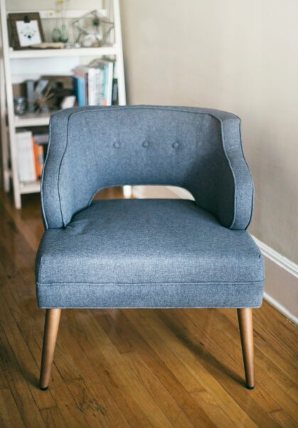 Person taking photo of grey padded chair inside room