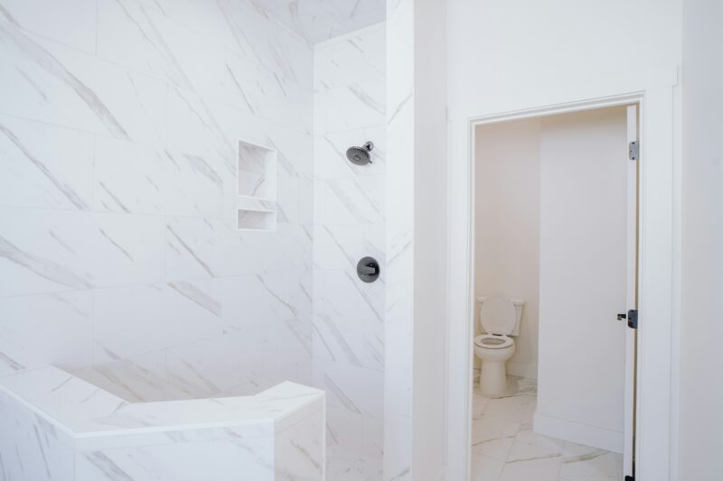 a white bathroom with a toilet and a shower