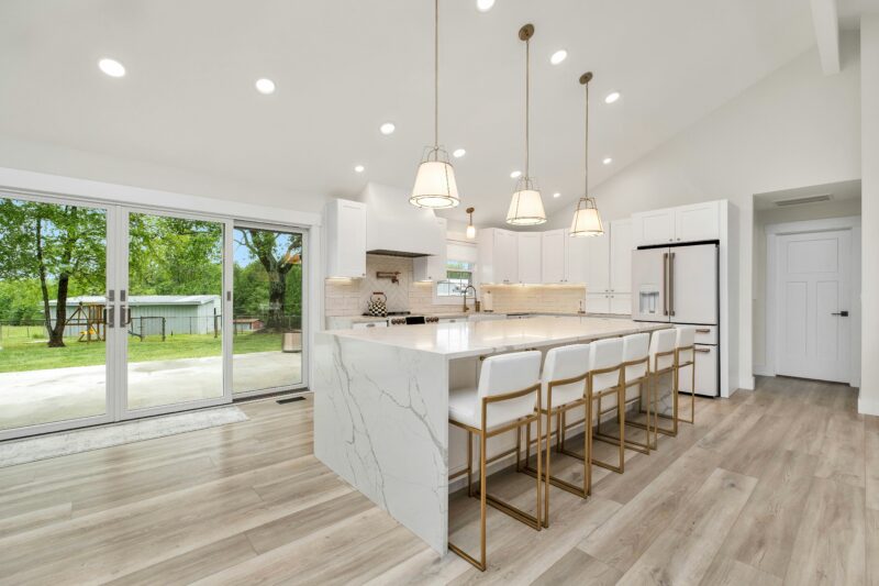 A large kitchen with a center island and marble counter tops