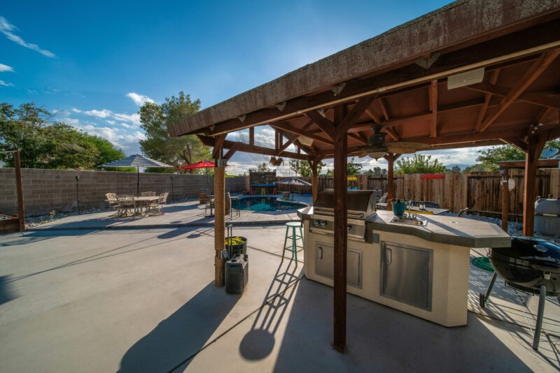 a covered patio with a grill and a table