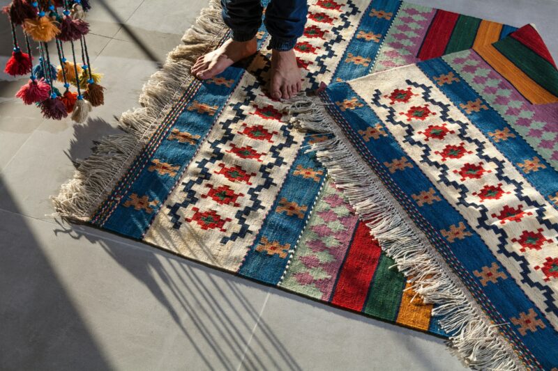 person in blue denim jeans standing on white blue and red area rug