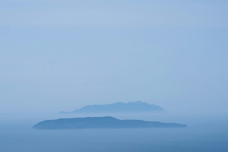 an island in the middle of the ocean on a foggy day