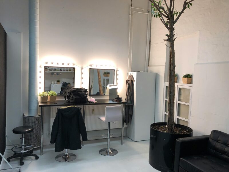 A well-lit vanity setup featuring a mirror, stool, and cozy decor in a modern indoor space.