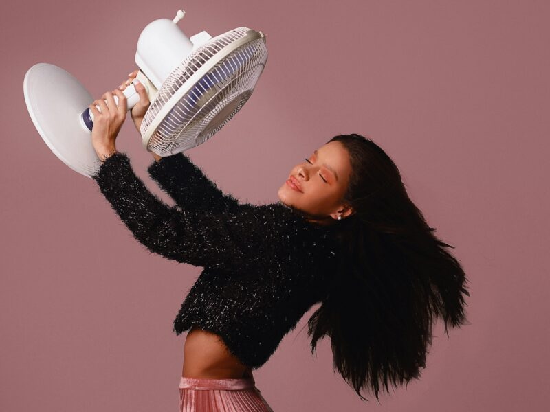 Artistic studio portrait of a young woman with a fan, embracing summer vibes.