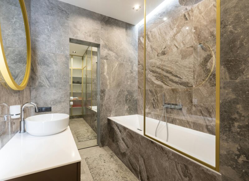 Luxurious bathroom featuring marble tiles, a round mirror, and modern fixtures, creating a refined and sophisticated space.