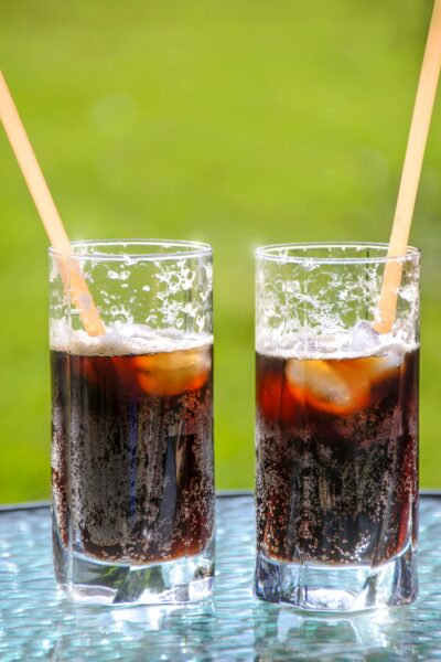 Two iced glasses of cola with straws, perfect for summer refreshment.