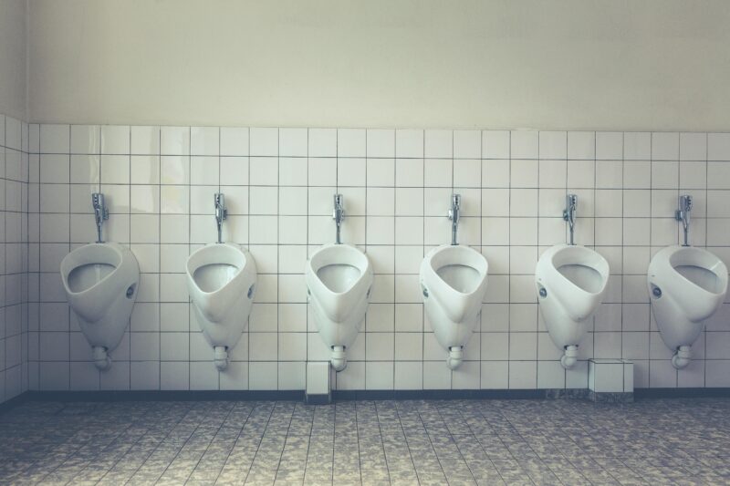 A modern and tidy restroom with a row of white urinals and tiled walls and floors.