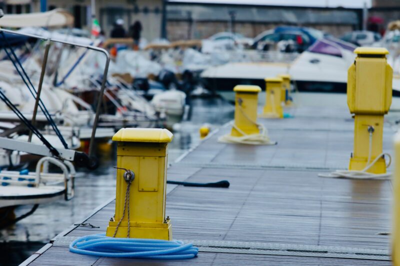 Colorful marina in Salerno, Italy, showcasing boats and yellow bollards on a dock.