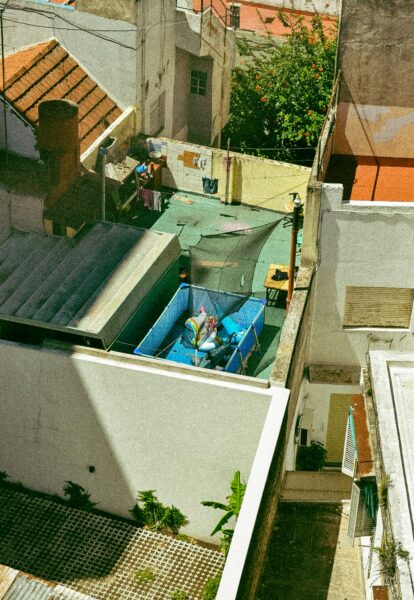 Aerial view of an urban backyard featuring a small pool amidst residential buildings.