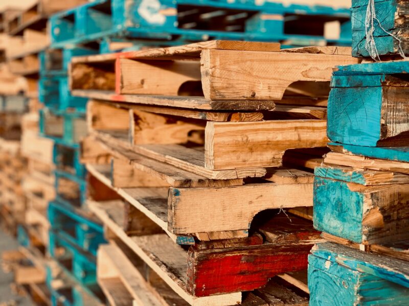 Close-up of colorful stacked wooden pallets in outdoor sunlight.