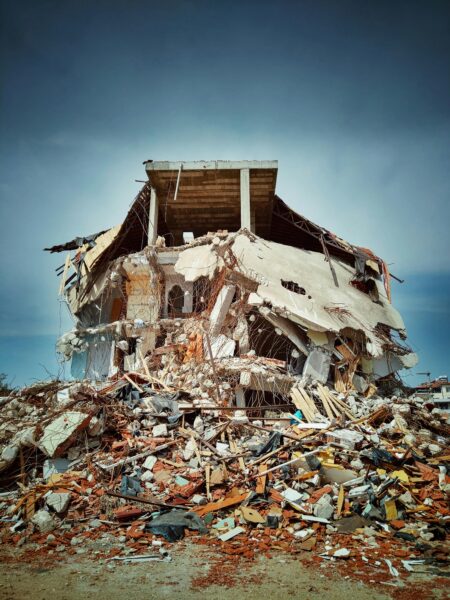 A collapsed building stands precariously amidst a vast expanse of rubble and debris, illustrating destruction.