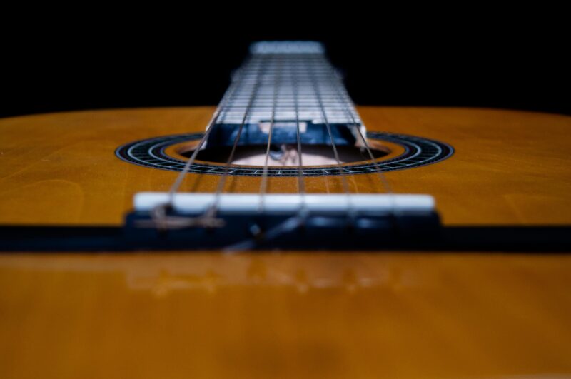 Detailed close-up shot of the strings on a classical acoustic guitar, focusing on the soundhole.