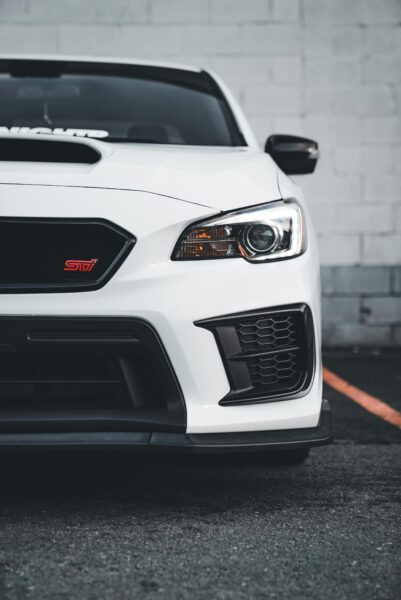 Stylish white Subaru WRX with sleek headlight design, captured stationary in an urban setting.