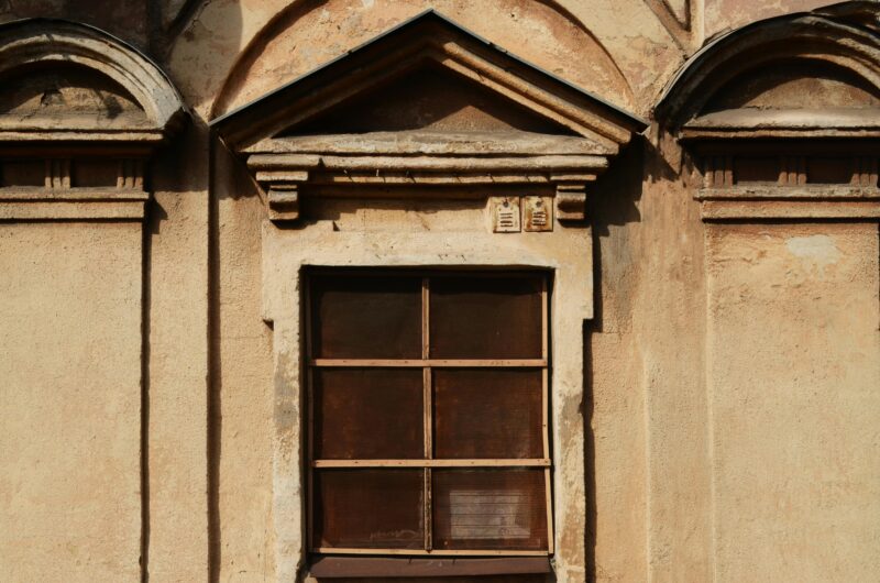 A vintage window on a rustic building exterior showcasing classic architectural details.