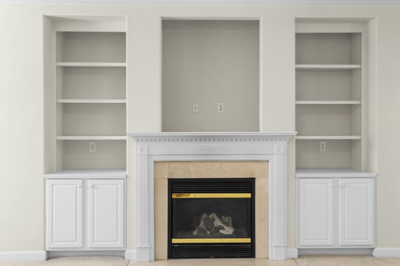 A luxurious white interior with built-in shelves and a central fireplace, perfect for modern homes.