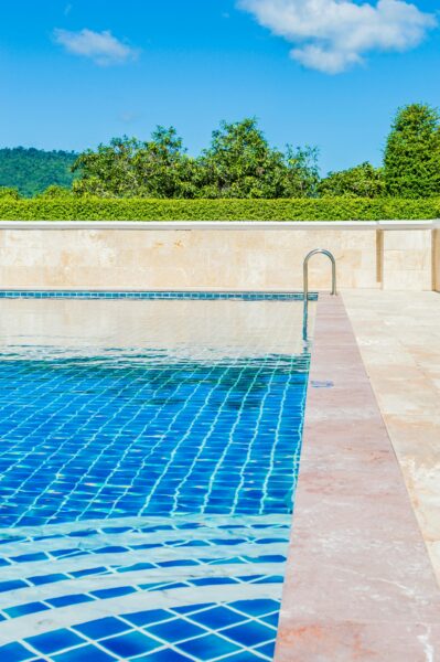 Bright and tranquil poolside scene, capturing a turquoise swimming pool under a clear blue sky.