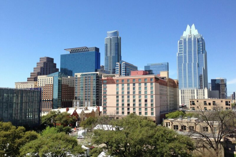 A vibrant daytime cityscape of downtown Austin, showcasing modern architecture and towering skyscrapers.