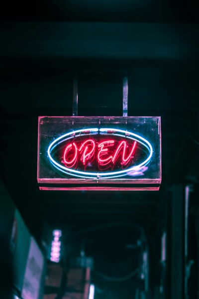 Glowing neon 'Open' sign illuminating the night street with vivid colors.