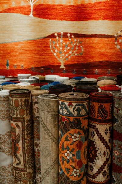 A vibrant collection of traditional carpets on display in a market setting, rich in color and pattern.