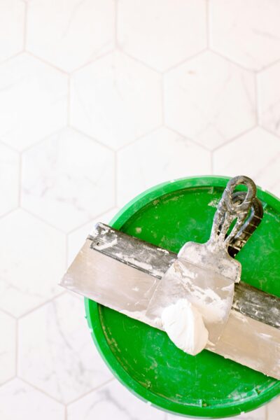 Close-up of a trowel and putty on a green bucket, ideal for renovation projects.