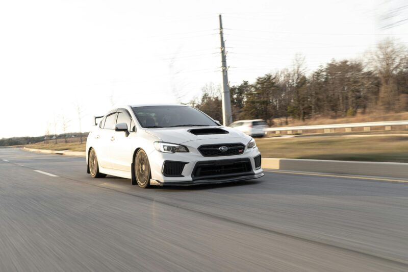 White Subaru WRX in motion on the highway, capturing speed and performance.