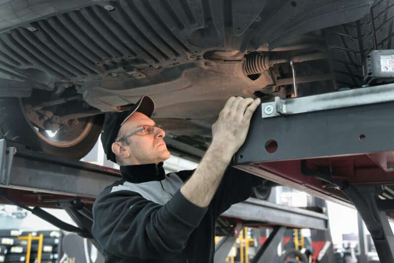 Professional mechanic conducting vehicle inspection in an auto workshop.