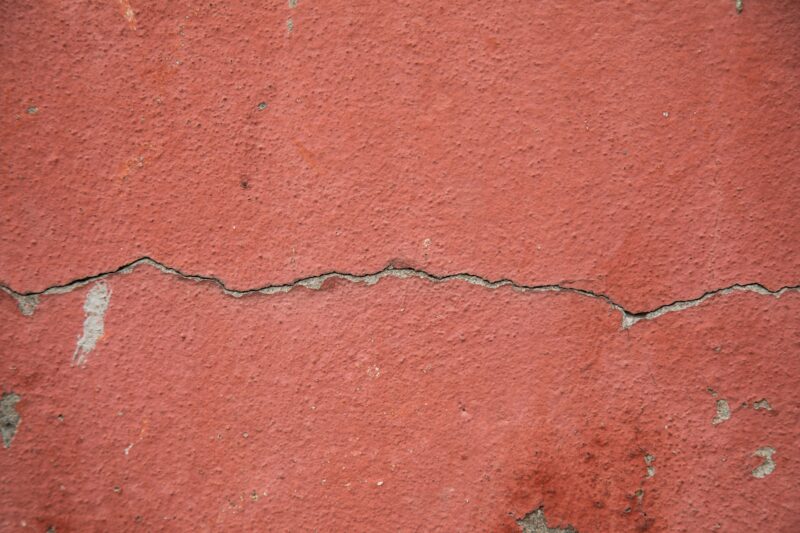 High-resolution image of a cracked red-painted concrete wall surface for texture background.