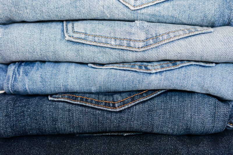 Closeup of stack of blue denim pants neatly arranged according to color from lightest to darkest