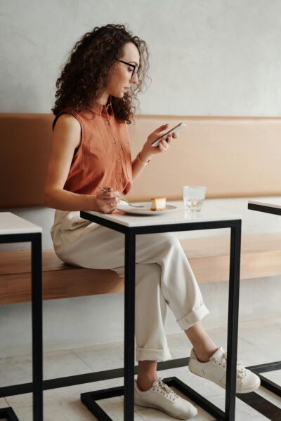 A young woman enjoys a quiet moment at a coffee shop, checking her phone while seated.