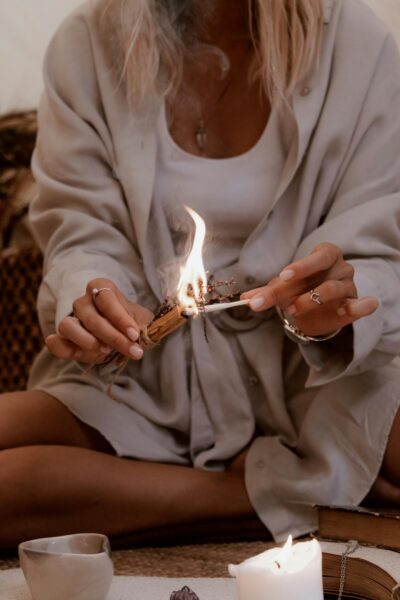 A woman performing a candle ritual indoors, creating a warm and cozy atmosphere.