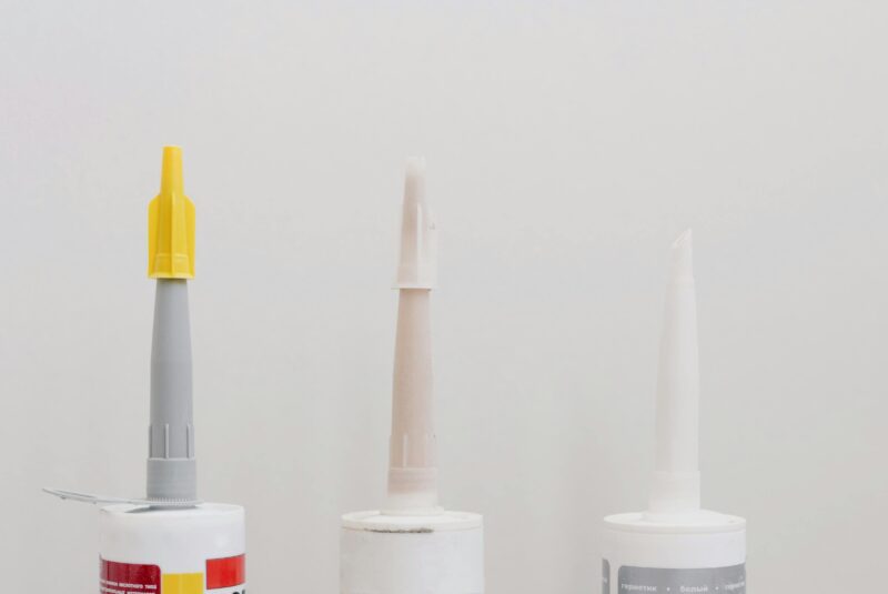 Set of various plastic tubes with glue for renovation works in workshop against white background