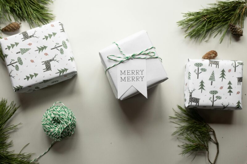 Top view of Christmas gift boxes wrapped in festive paper with pine branches and twine.