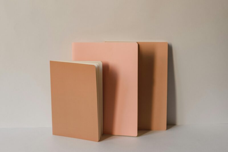 Three peach-colored notepads standing on a neutral background, showcasing minimalistic stationery design.