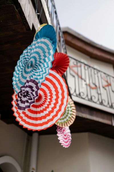 Vibrant paper fans hanging outdoors, adding a festive touch to an outdoor space.