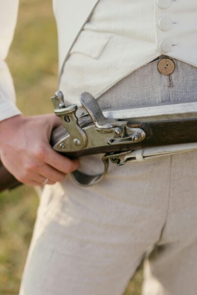 Close-up view of a rifle trigger during a historical reenactment with focus on hand and weapon.