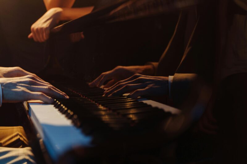 Close-up shot of hands playing a grand piano, capturing the art of music in a warm, intimate setting.