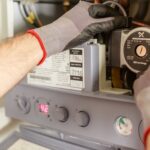 Free Close-up of hands adjusting a boiler system with precise instrumentation, showing maintenance work. Stock Photo