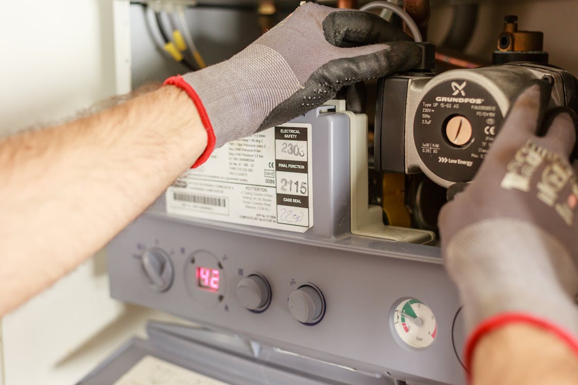 Free Close-up of hands adjusting a boiler system with precise instrumentation, showing maintenance work. Stock Photo