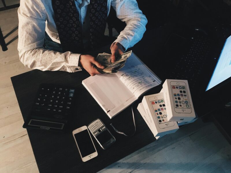 Businessman organizing finances with tech devices and cash on desk, financial planning, analysis.