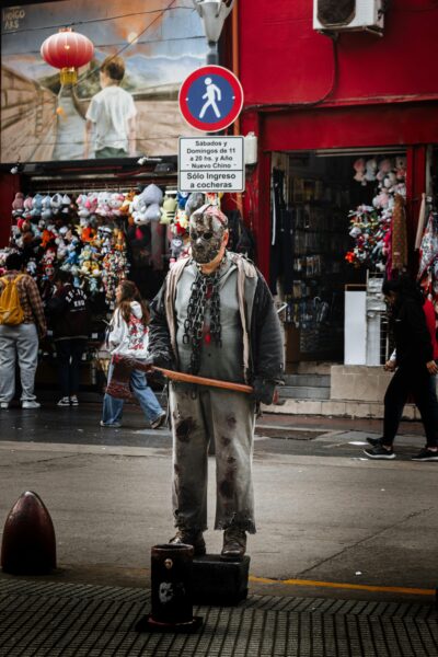 Street performer wearing a Jason costume in a bustling Buenos Aires marketplace.