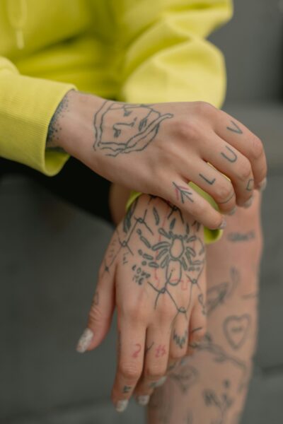 Detailed shot of hands with tattoos, featuring artistic designs and hand-lettering.