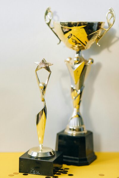 Close-up of two sleek silver trophies showcasing success and achievement against a yellow background.