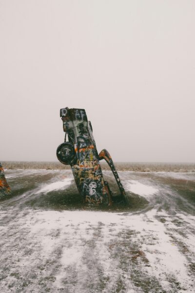 Abandoned car art installation in snow-filled barren landscape.