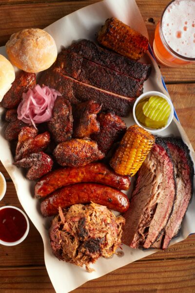 Top view of a succulent barbecue meat platter featuring sausages, brisket, and corn, perfect for foodies.