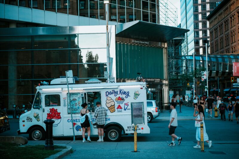 A vibrant street scene in Toronto featuring an ice cream truck and pedestrians.