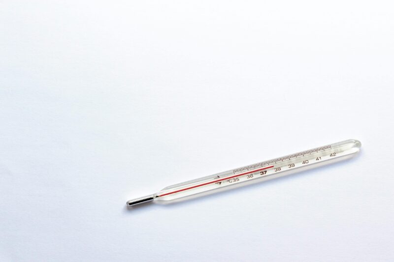 A glass clinical thermometer on a plain white background, symbolizing healthcare and medical precision.