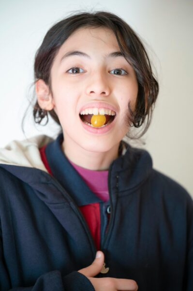 A joyful young child indoors with a snack, showcasing a bright smile and playful expression.